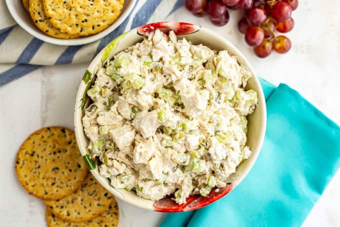 A bowl of classic chicken salad with crackers and grapes nearby