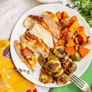White dinner plate with chicken and vegetables with bacon and seasonings
