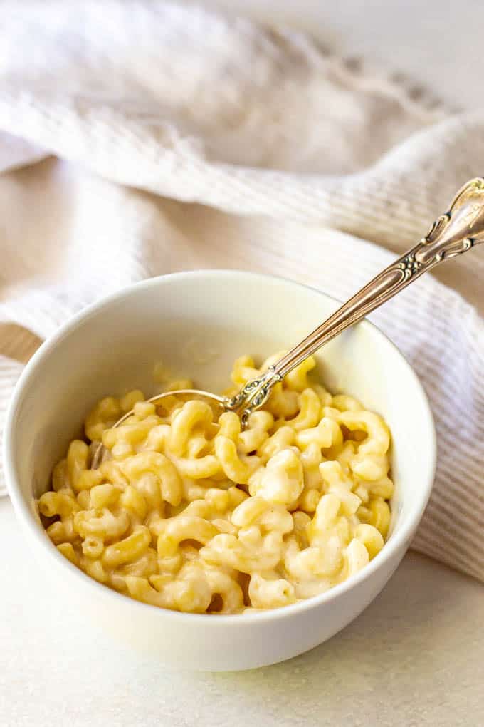 Macaroni and cheese made in the microwave served in a white bowl with a spoon
