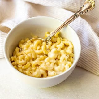 Cheesy pasta served in a white bowl with a spoon
