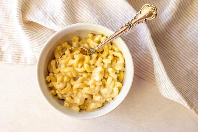 Cheesy macaroni served in a white bowl with a spoon