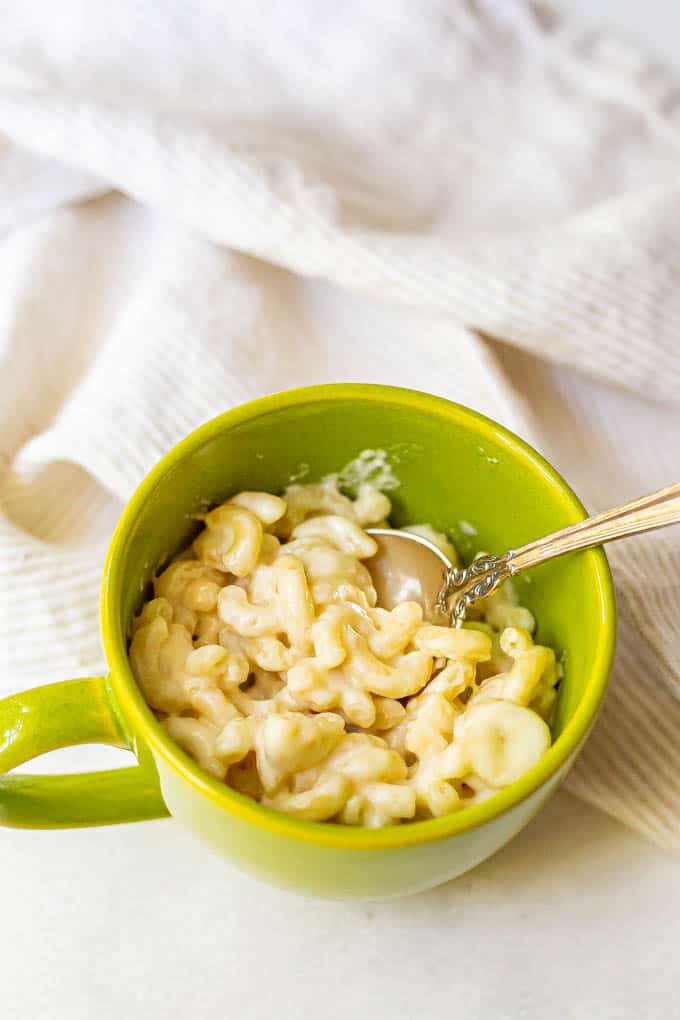 Microwave mac and cheese in a green mug with a spoon