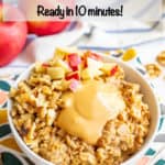 A bowl of peanut butter oatmeal topped with peanut butter, chopped apples and walnuts.