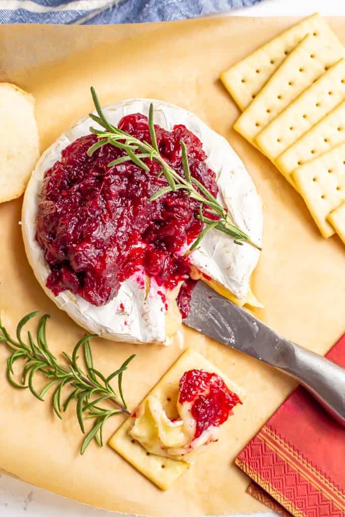 Holiday baked brie with cranberry sauce and rosemary, served with crackers