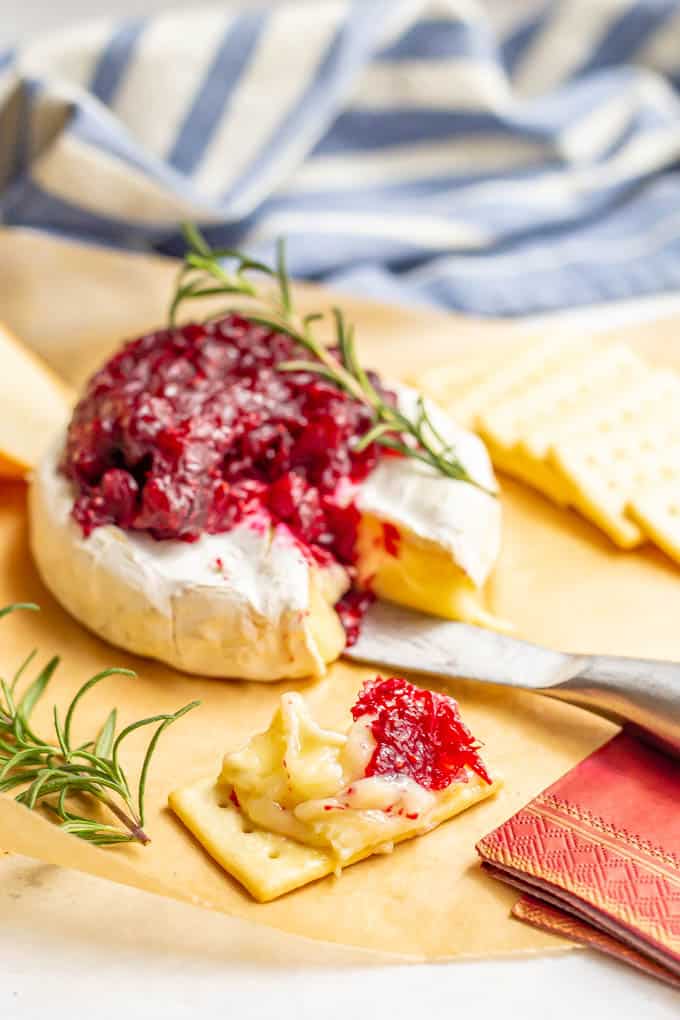 Baked brie with cranberry sauce sliced and served with crackers