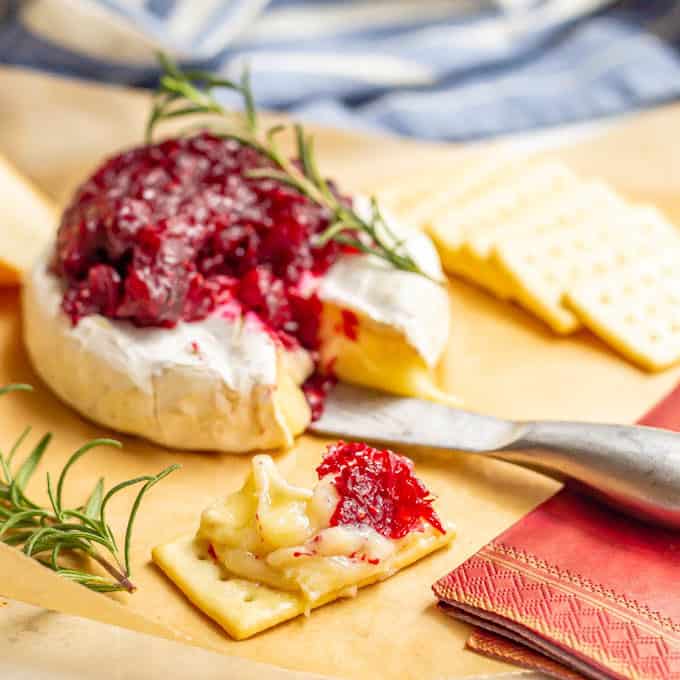 A cracker spread with brie cheese and cranberry sauce