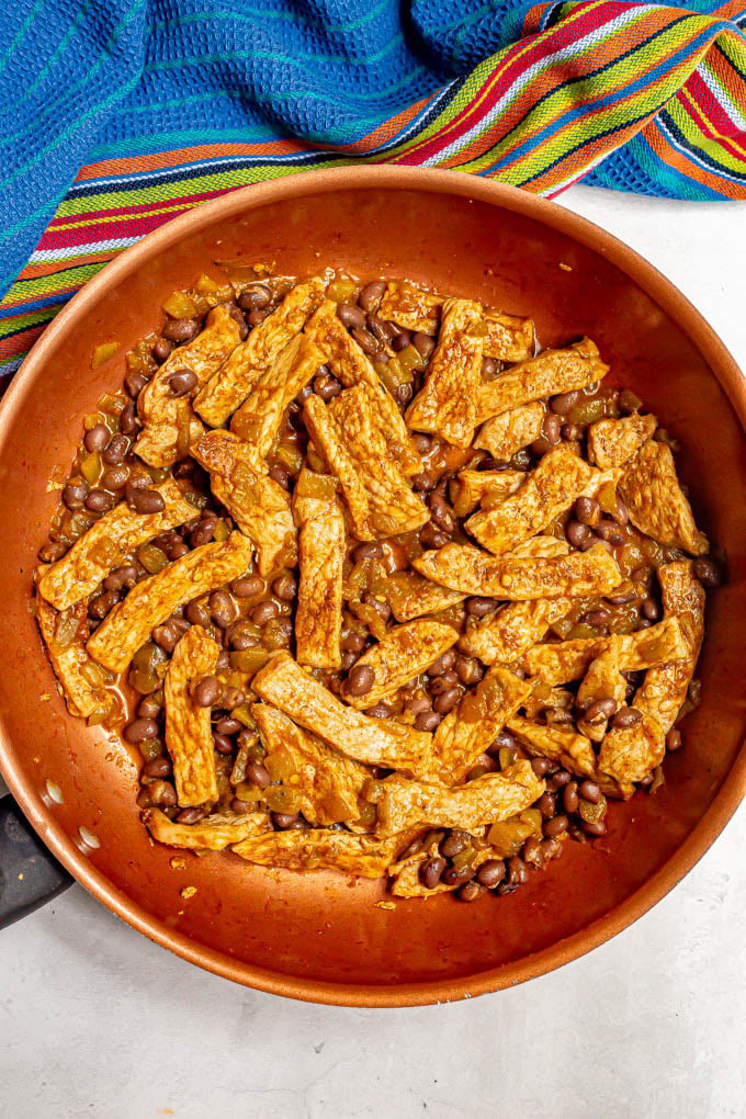 Skillet with cooked pork strips, black beans and green chilies