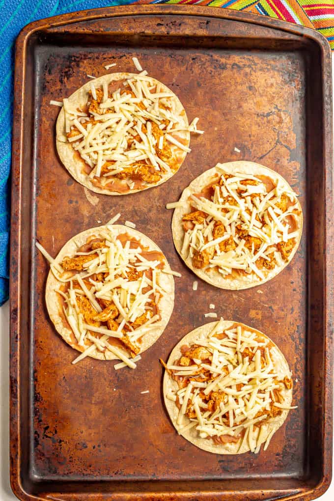 Baked corn tortillas with refried beans, leftover turkey and cheese on a baking sheet before baking