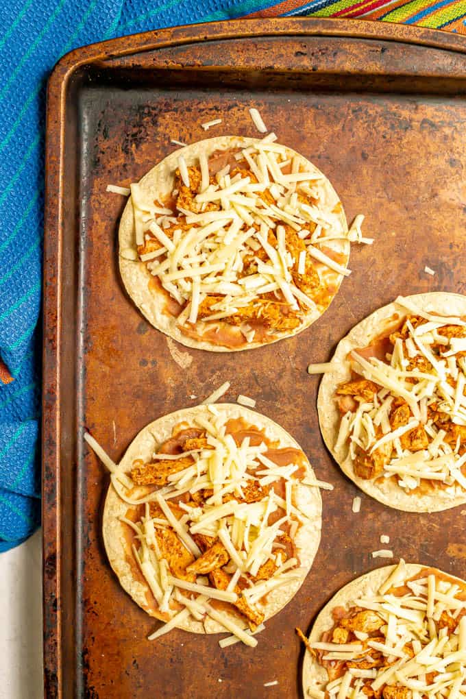 Baked corn tortillas with refried beans, leftover turkey and cheese on a baking sheet before baking