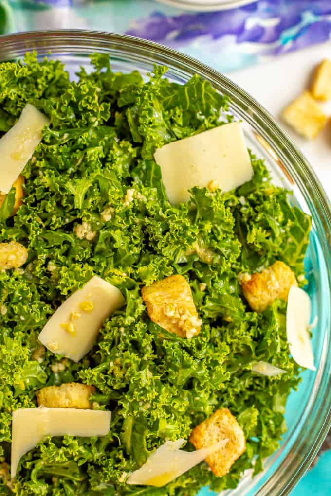 Close up of kale salad in a glass bowl with croutons, Parmesan cheese and Caesar dressing