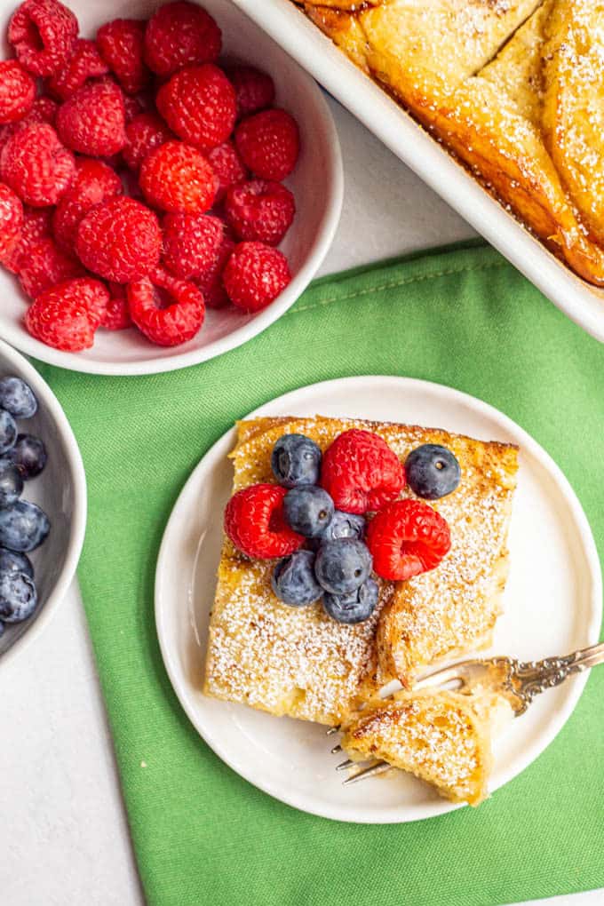 Baked French toast served on a white plate with fresh berries on top