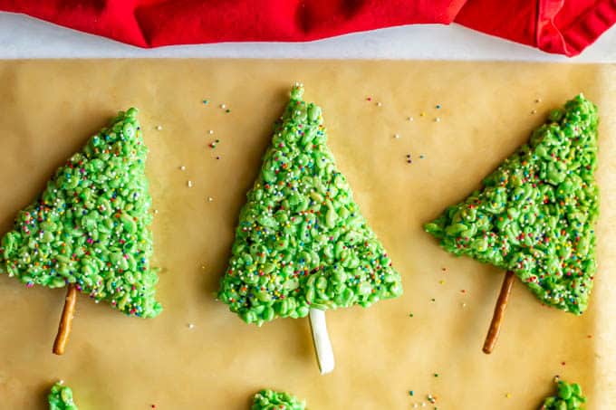 Rice Krispies trees with sprinkles on a piece of parchment paper