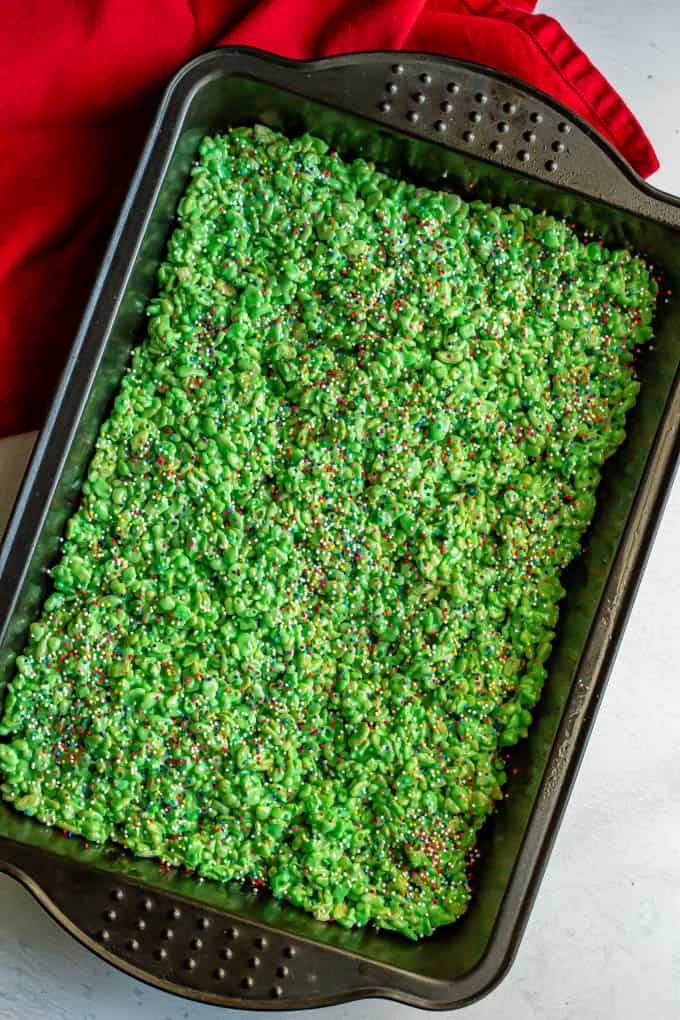 Green Rice Krispie treats with sprinkles setting up in a pan