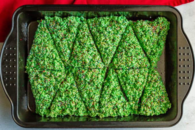 Pan of green crispy rice treats topped with sprinkles and cut into triangles