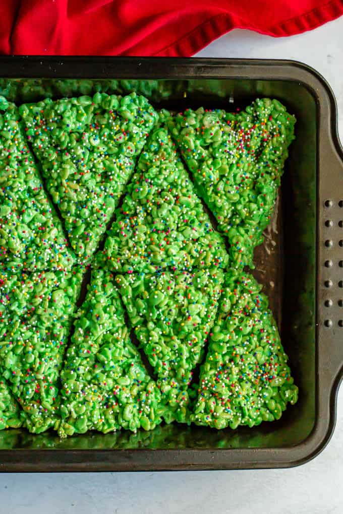 Pan of green crispy rice treats topped with sprinkles and cut into triangles