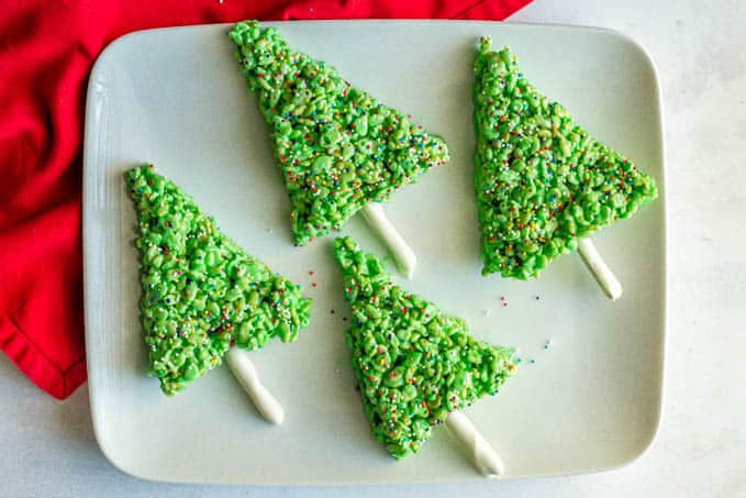 A group of green holiday Rice Krispie trees with sprinkles on a white platter