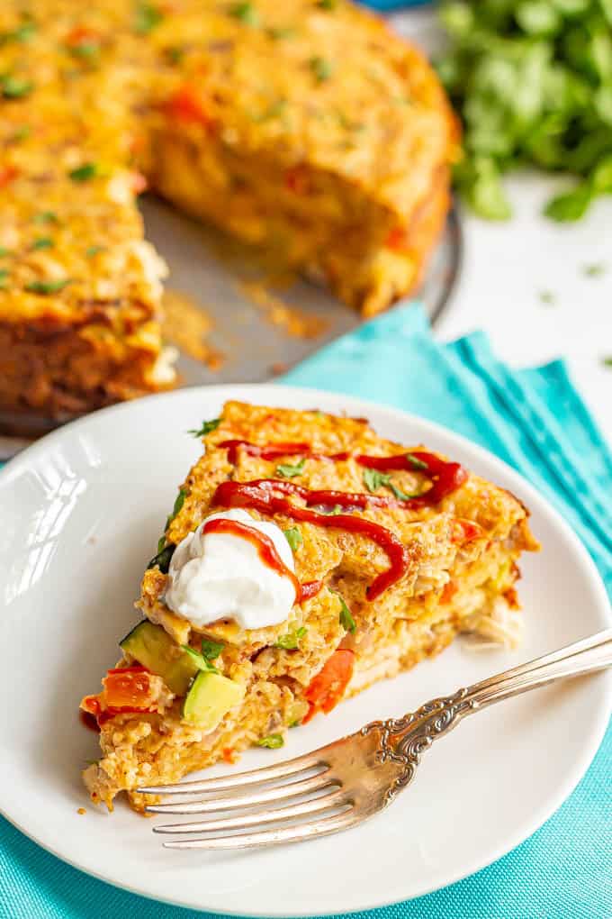 A slice of southwestern chicken and veggie frittata served on a white plate with a fork