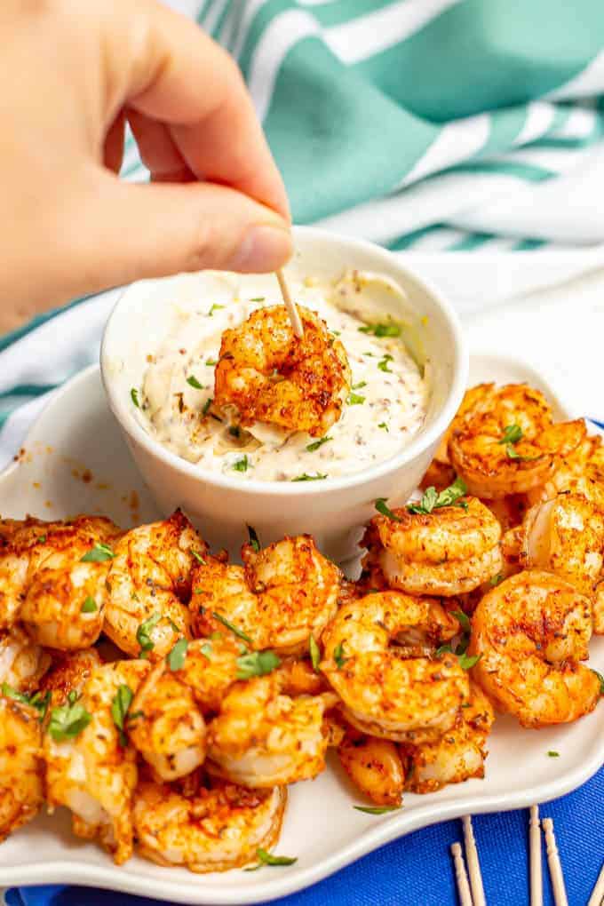 A roasted shrimp being dipped into a creamy sauce