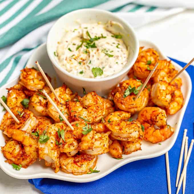 White serving tray with spicy roasted shrimp with toothpicks and a creamy dip