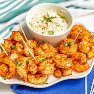 White serving tray with spicy roasted shrimp with toothpicks and a creamy dip