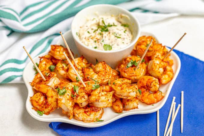 White serving tray with spicy roasted shrimp with toothpicks and a creamy dip