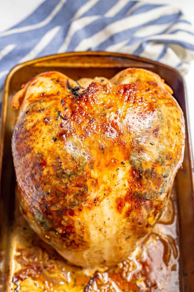A cooked turkey breast in the roasting pan with juices at the bottom