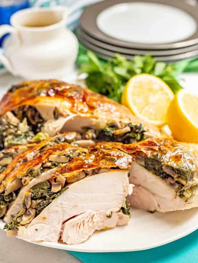 Close up of stuffed spinach and mushroom turkey breast served on a large white platter