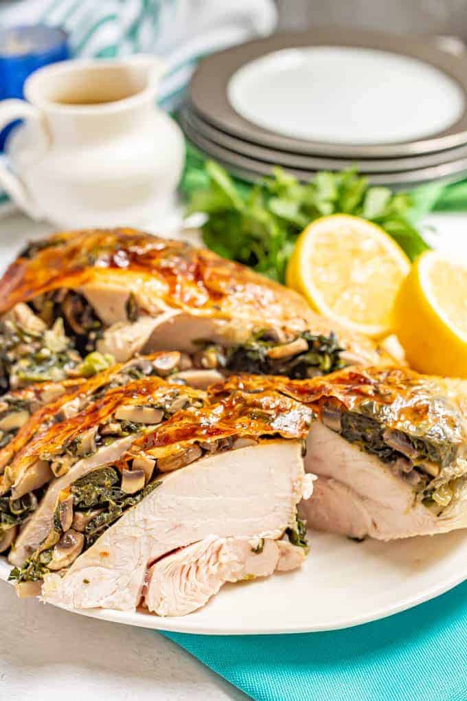 Close up of stuffed spinach and mushroom turkey breast served on a large white platter