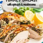 A boneless turkey breast with a spinach and mushroom stuffing served on a white platter with lemon halves and parsley for garnish.
