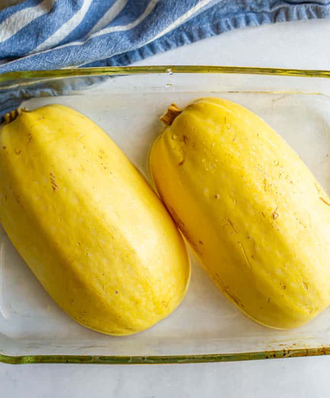 Spaghetti squash halves upside down in a glass pan before being cooked