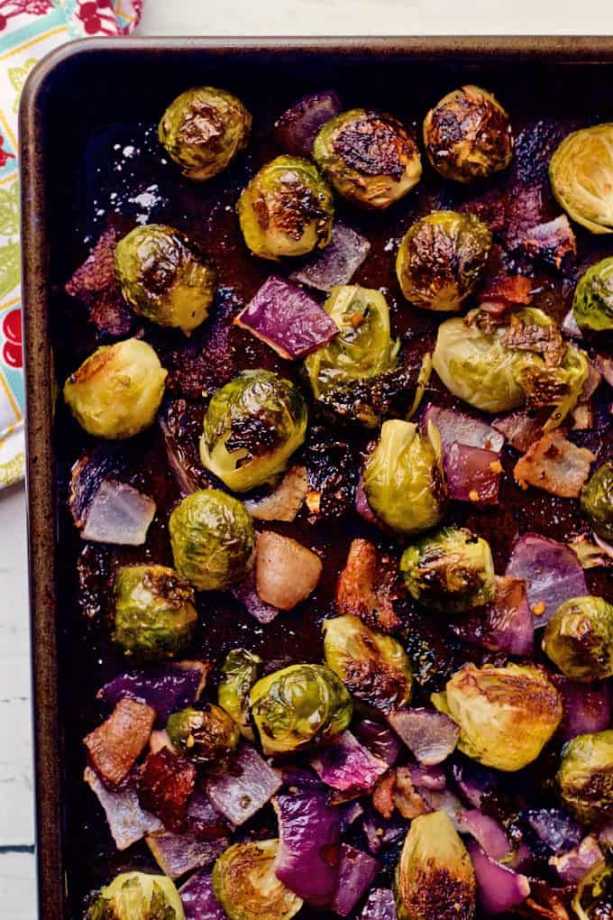 Brussels sprouts are roasted with bacon and chunks of red onion for a super flavorful veggie side dish that everyone will love! #brusselssprouts #veggiesides #sidedish #roastedveggies