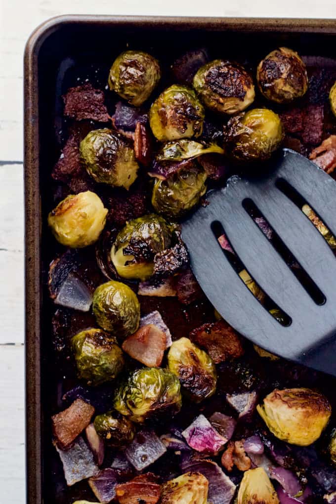 Roasted Brussels sprouts on a sheet pan with a spatula