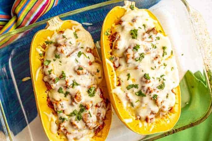 Baked spaghetti squash with chicken enchilada and melted cheese in a casserole dish