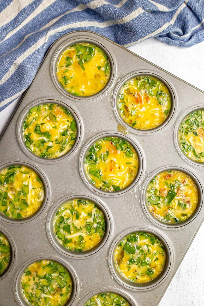 Filled muffin tin with a spinach egg mixture before being baked