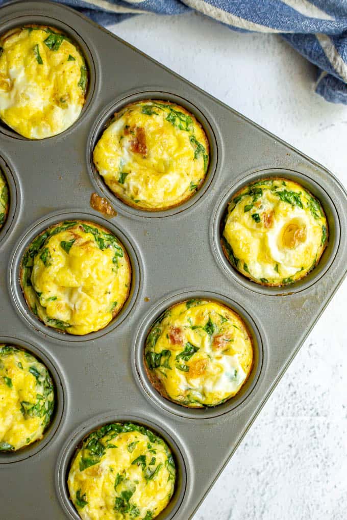 Spinach, bacon and cheese egg muffins in a muffin tin after being baked