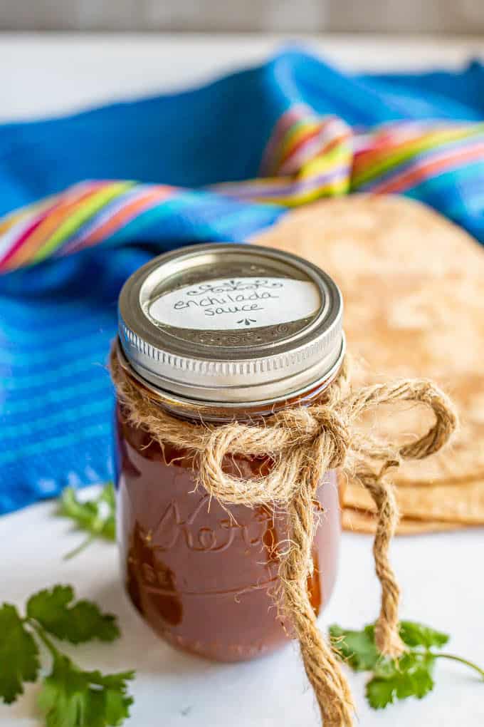 A jar of enchilada sauce with a label on top and a rope tied into a bow around it