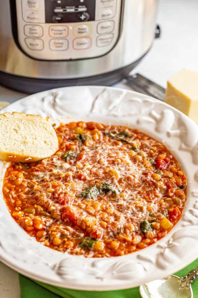 Instant Pot lentil soup served in a white bowl with Parmesan cheese and fresh bread