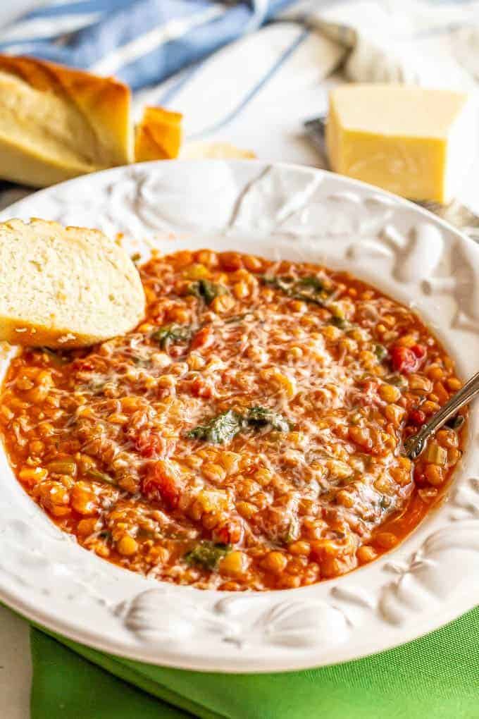 Lentil soup served in a white bowl with Parmesan cheese and fresh bread