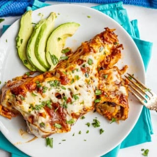 Sweet potato black bean enchiladas served on a plate with cilantro and avocado slices