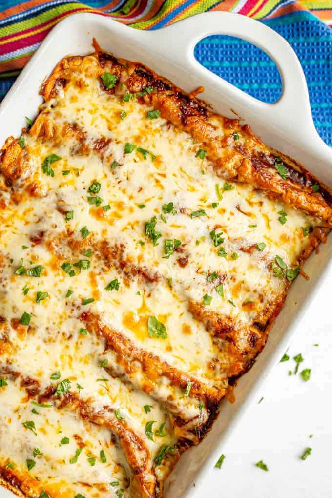 Bubbly cheesy baked sweet potato black bean enchiladas in a white casserole dish