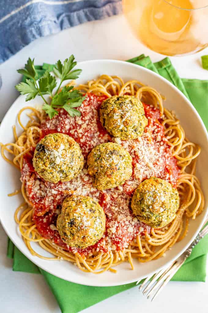 Vegetarian meatballs on top of a bed of spaghetti noodles with marinara sauce in a white bowl