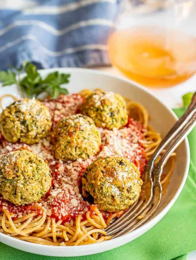 Baked zucchini meatballs on top of spaghetti noodles with marinara sauce in a white bowl