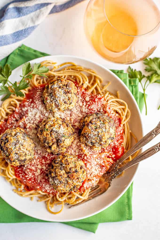 Mushroom meatballs served over spaghetti noodles and marinara in a white bowl with forks tucked in