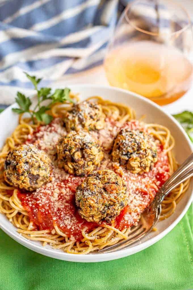 Vegetarian mushroom meatballs served over spaghetti noodles and marinara in a white bowl with forks tucked in