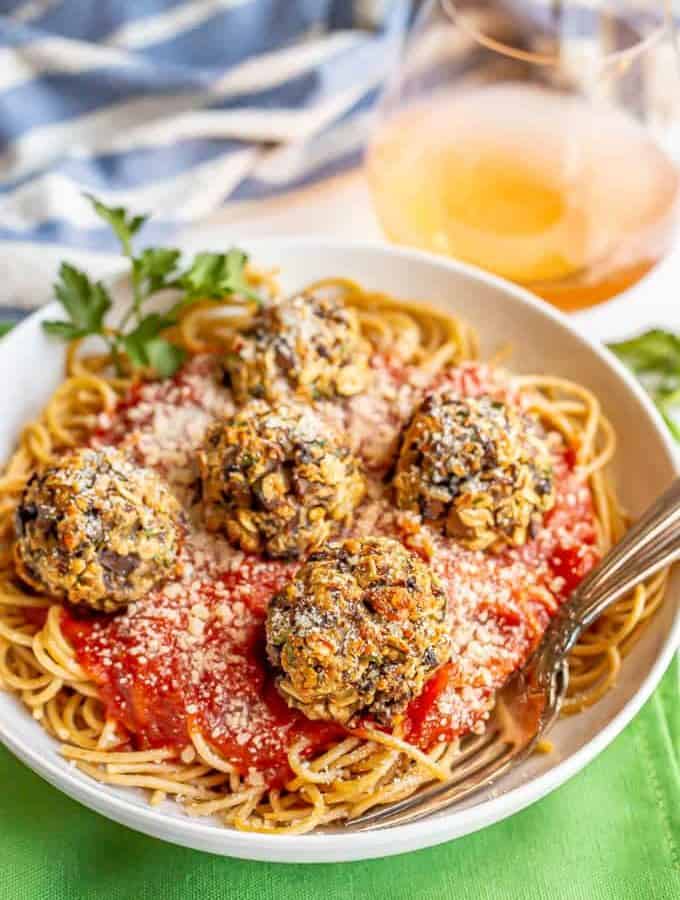 Vegetarian mushroom meatballs served over spaghetti noodles and marinara in a white bowl with forks tucked in