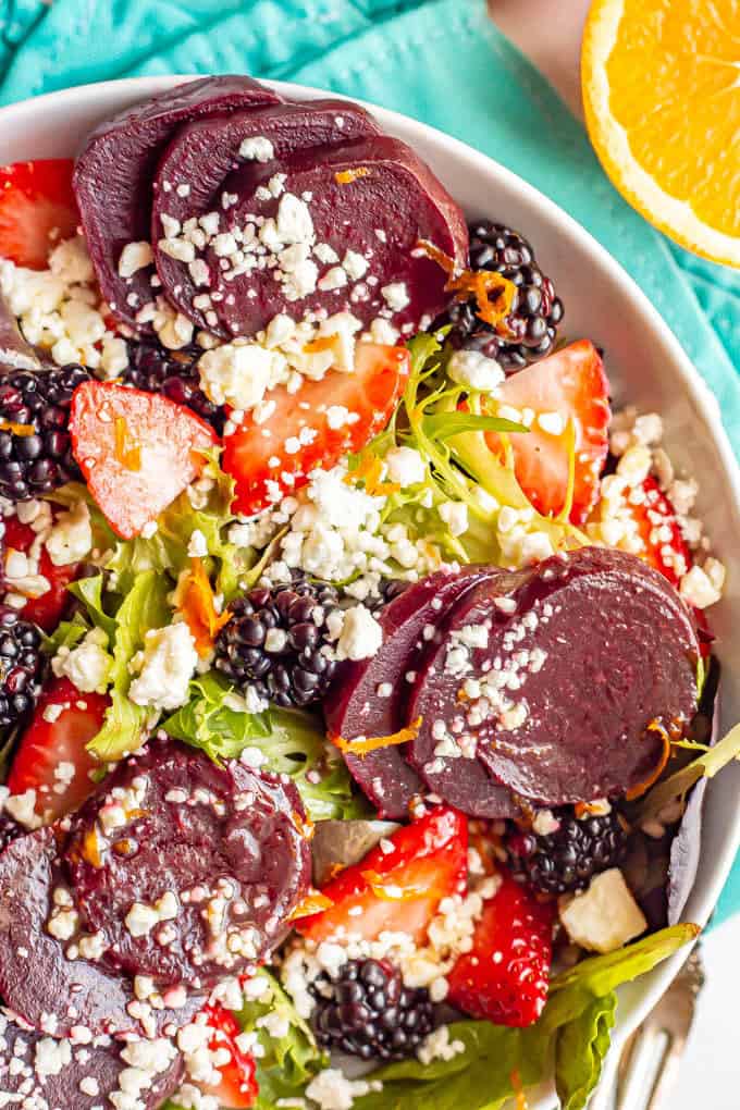 Close up of a salad bowl with mixed greens, beets, fresh berries sand feta cheese