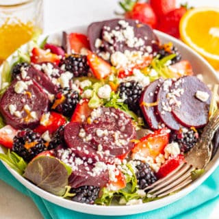 A salad bowl with mixed greens, beets, fresh berries sand feta cheese