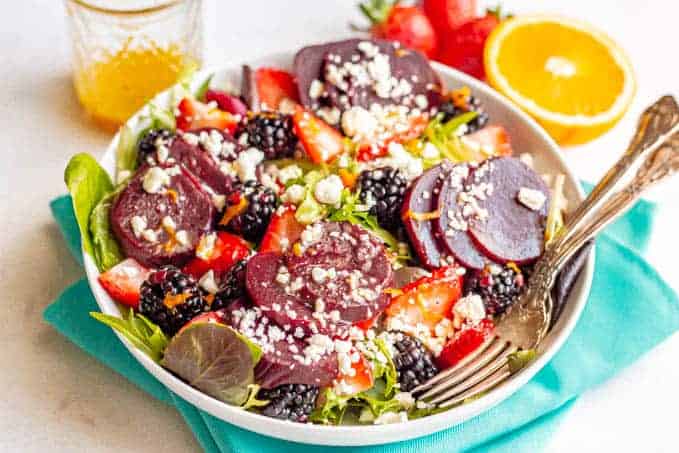 A salad bowl with mixed greens, beets, fresh berries sand feta cheese