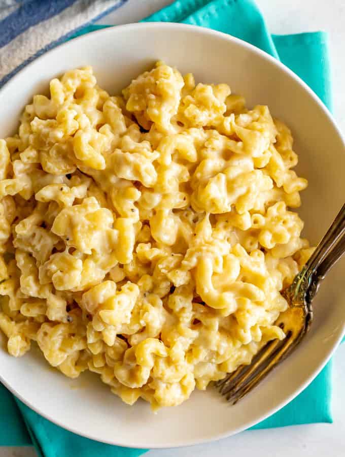 Creamy crock pot mac and cheese in a large serving bowl with two forks alongside