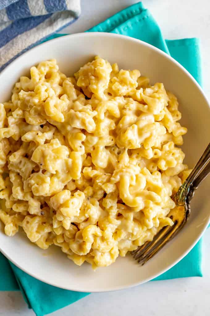 Creamy crock pot mac and cheese in a large serving bowl with two forks alongside